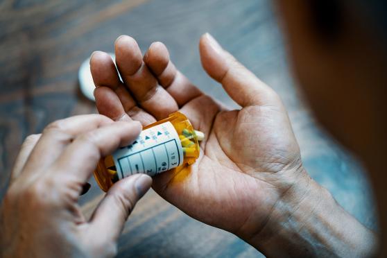 Pills from a pill bottle being dispensed onto a hand